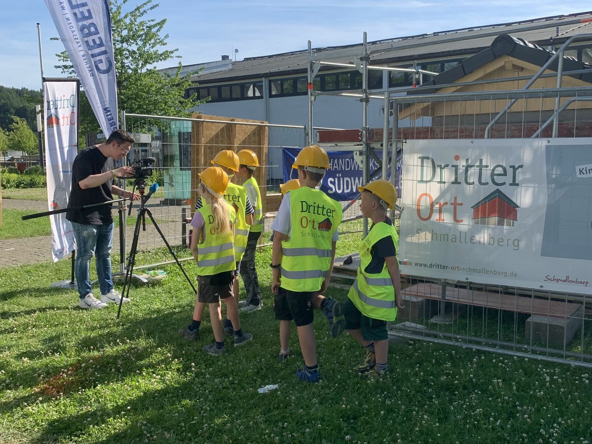 Ein Kameramann von Sat.1 NRW interviewt die Kinder der Kinderbaustelle vor ihrem selbst gebauten Haus. 